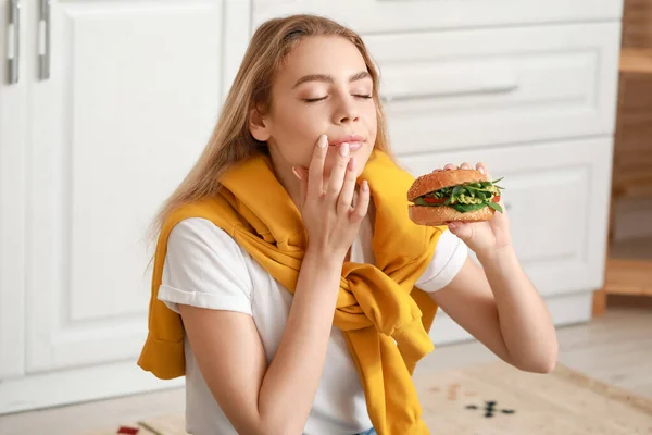 Jovem Mulher Comendo Saboroso Hambúrguer Vegan Cozinha — Fotografia de Stock