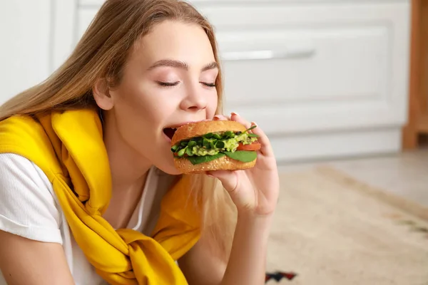 Jovem Mulher Comendo Saboroso Hambúrguer Vegan Cozinha — Fotografia de Stock