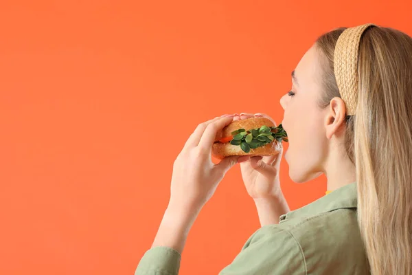 Jonge Vrouw Eten Smakelijke Veganistische Hamburger Kleur Achtergrond — Stockfoto