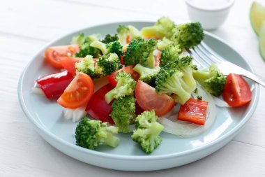 Hafif ahşap zemin üzerinde brokoli bulunan lezzetli bir salata tabağı, yakın plan.