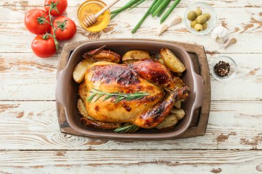 Hafif ahşap arka planda lezzetli tavuk, bal ve sebzeli fırın yemeği.