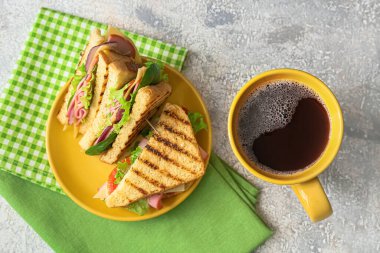 Lezzetli sandviçler ve açık arkaplanda bir fincan kahve.