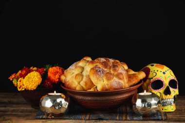 Ölülerin ekmeği ve masa üzerinde koyu arka planda boyanmış kafatası. Meksika Ölüler Günü 'nün Kutlaması (El Dia de Muertos)