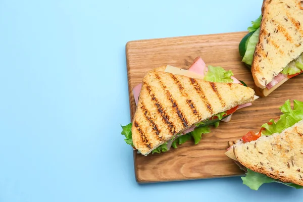 Tablero Con Sabrosos Sándwiches Sobre Fondo Color —  Fotos de Stock