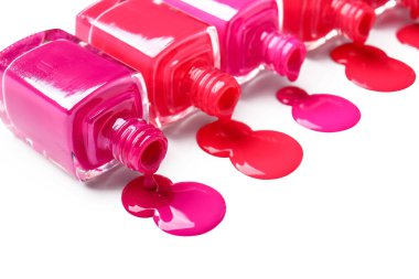 Beyaz arka planda devrilmiş oje şişeleri ve lekeler.