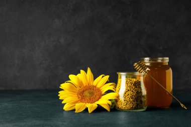 Arı poleni kavanozları ve koyu arkaplanda bal