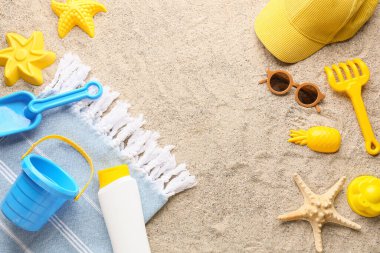 Çocuklar için plaj aksesuarları ve kumda bir şişe güneş kremi.