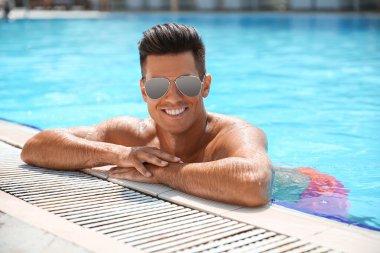 Yüzme havuzunda dinlenen yakışıklı adam.