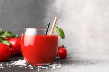 Gri arkaplanda bir bardak lezzetli domates suyu.