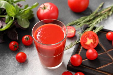 Gri arkaplanda bir bardak lezzetli domates suyu.