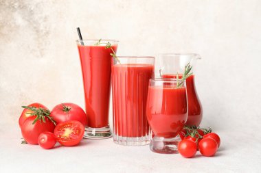 Açık arkaplanda bir bardak lezzetli domates suyu.