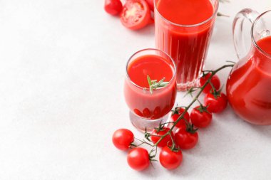 Açık arkaplanda bir bardak lezzetli domates suyu.