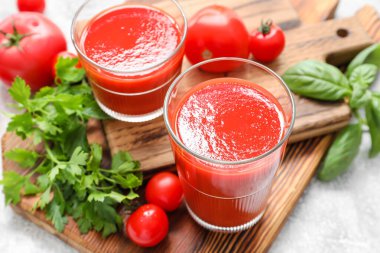 Açık arkaplanda bir bardak lezzetli domates suyu.