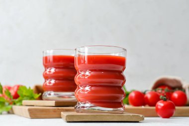 Açık arkaplanda bir bardak lezzetli domates suyu.