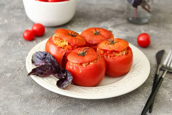 Plate with tasty stuffed tomatoes on grunge background