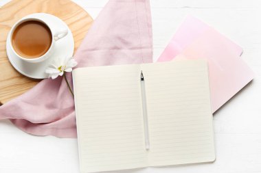 Hafif ahşap arka planda defter, kalem ve bir fincan kahveyle kompozisyon