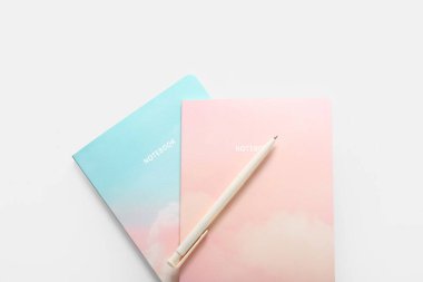 Beyaz arkaplanda stil defterleri ve kalem