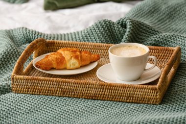 Bir fincan kahve ve örülmüş ekoseli kruvasan.