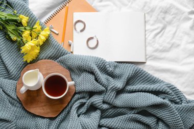 Yatağında çiçek ve aksesuar olan bir fincan çay.
