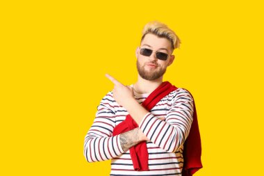 Yakışıklı genç adam arka planda bir şeye işaret ediyor.