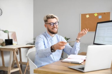 Evde dizüstü bilgisayarı olan genç bir adam sohbet ediyor.