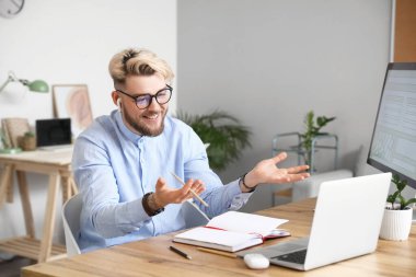 Evde dizüstü bilgisayarı olan genç bir adam sohbet ediyor.