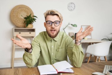 Genç adam evde video sohbeti yapıyor.