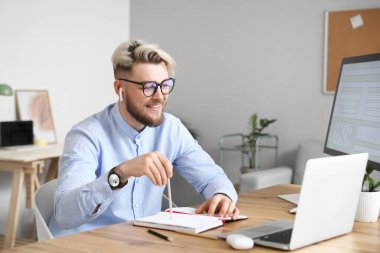 Evde dizüstü bilgisayarı olan genç bir adam sohbet ediyor.