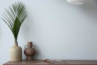 Işık duvarının yanında vazoları olan raflar.