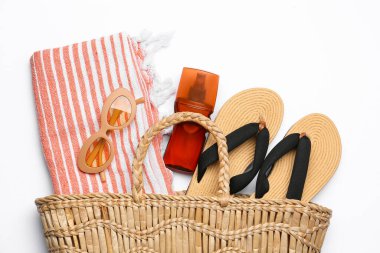 Plaj aksesuarları ve beyaz arka planda güneş kremi olan şık bir çanta.