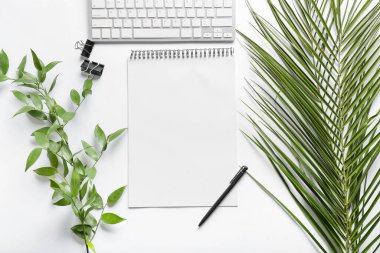 Beyaz arkaplanda boş defter, kalem ve avuç içi yaprakları olan kompozisyon