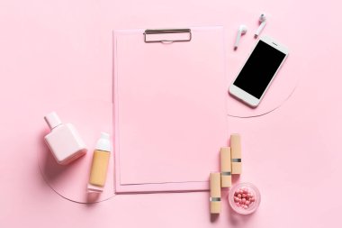 Renk arkaplanında boş kağıt, cep telefonu, kulaklık ve kozmetik bileşimi
