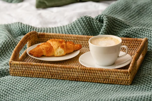 Bir fincan kahve ve örülmüş ekoseli kruvasan.