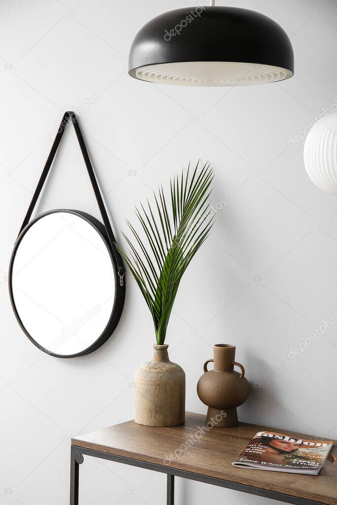 Shelf with vases near light wall