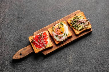 Koyu arkaplanda lezzetli tostları olan ahşap tahta tahta.