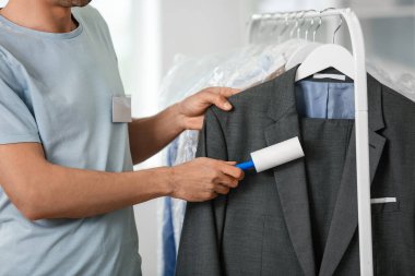 Modern kuru temizlemecide pamuklu bezle giysileri temizleyen bir erkek işçi.