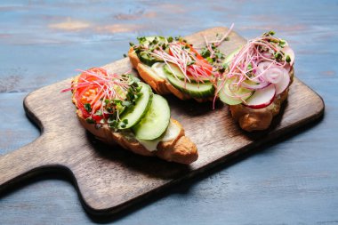 Sebzeli lezzetli kruvasanlar ve renkli ahşap arka planda mikro yeşil.