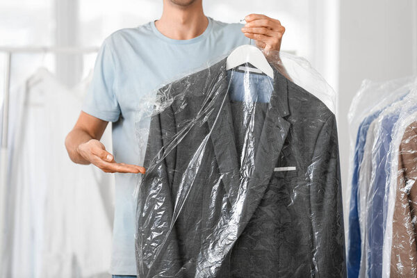 Male worker with clothes at modern dry-cleaner's