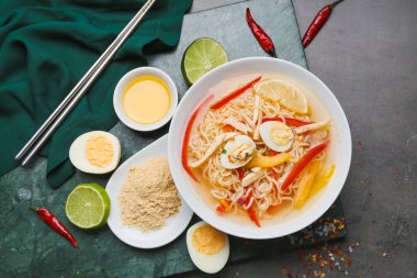 Bir kase lezzetli Tayland çorbası ve koyu arkaplanda malzemeler.