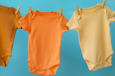 Bebek kıyafetleri ipe asılı, arka planda renk olarak, yakın plan