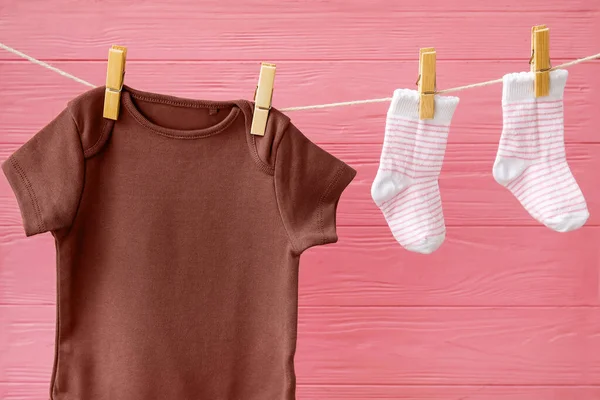 Bebek Kıyafetleri Ahşap Arka Planda Ipte Asılı Duruyor — Stok fotoğraf