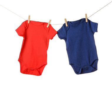 Beyaz arka planda bebek kıyafetleri asılı.