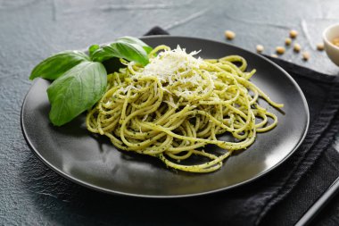 Koyu arkaplanda lezzetli pesto makarna tabağı, yakın plan.