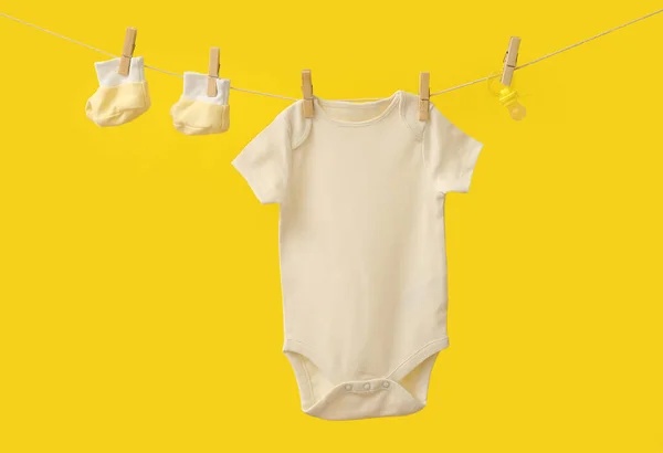 Babybekleidung Stiefel Und Schnuller Hängen Seil Vor Farbigem Hintergrund — Stockfoto