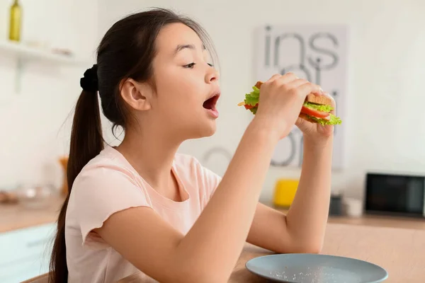 女の子食べるおいしいサンドイッチでキッチン — ストック写真