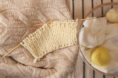 Masada bitmemiş giysileri olan örgü iğneleri, yakın plan.