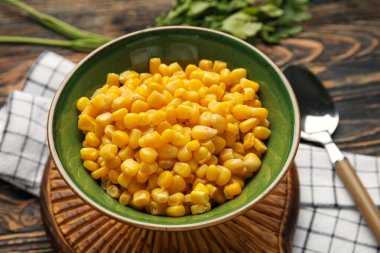 Tahta zemin üzerinde mısır taneleri olan bir kase, yakın plan.