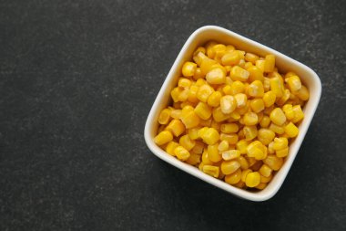 Koyu arkaplanda mısır taneleri olan bir kase