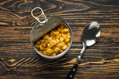 Tahta arka planda mısır taneleri olan teneke kutu, yakın plan.