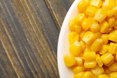 Tahta zemin üzerinde mısır taneleri olan plaka, yakın plan